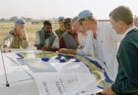 Enrique Ter Horst (third from right), Special Representative of the Secretary-General for Haiti, looking at a map of Haiti with members of the Canadian Battalion of UNSMIH. The group was planning a trip to the northern part of Haiti with a United Nations Development Programme specialist (second from right) to assess damage to the forest in Haiti's National Park. (1996) UN Photos/Eskinder Debebe | UN Multimedia