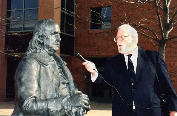 Charles Stuart Kennedy interviewing a bronze Benjamin Franklin on the campus of the Foreign Service Institute