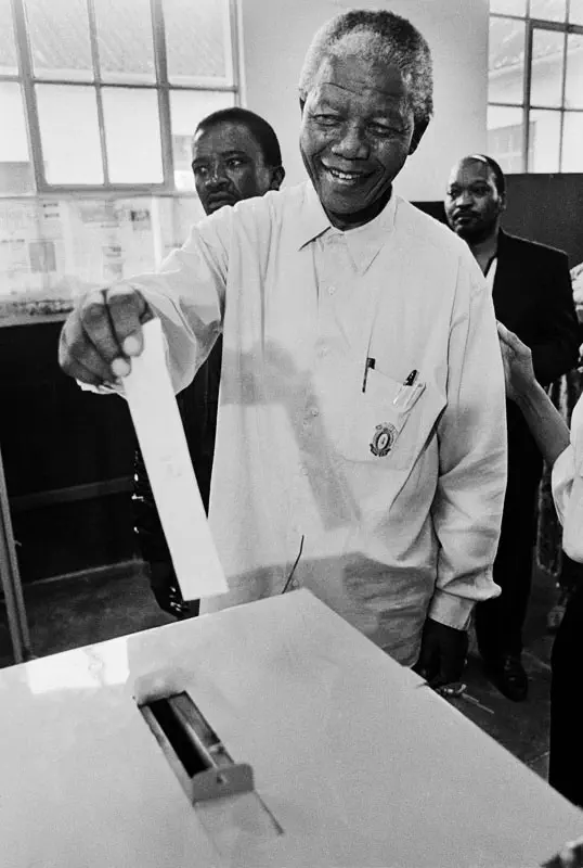 This is the official photo of Mandela casting his vote in the 1994 elections. It was the first time Mandela had voted in his life. It was taken at Ohlange School, Inanda, Durban by the IEC's official photographer, Paul Weinberg. It is one of only two images of this event.